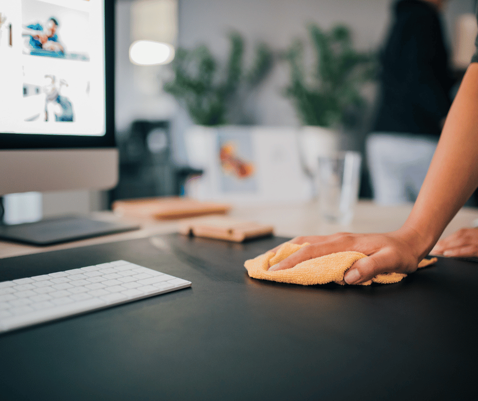 Image of desk with computer being wiped with a cloth